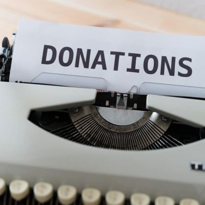 a close up of a typewriter with a donation sign on it