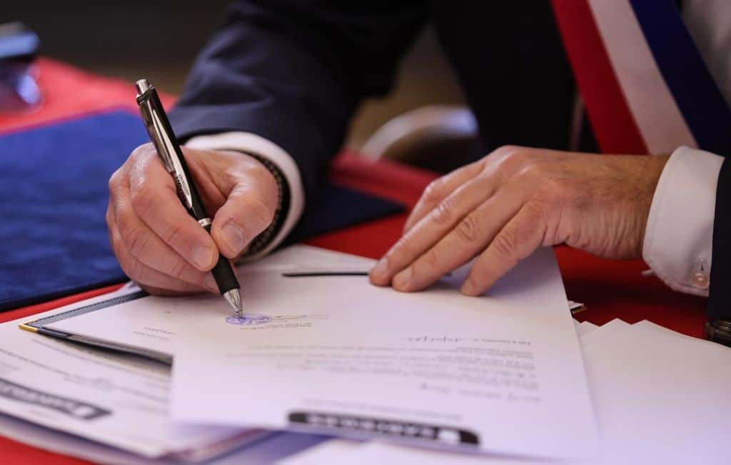 Trouver un avocat en droit des successions A person signs a document with a pen.
