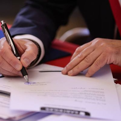 A person signs a document with a pen.