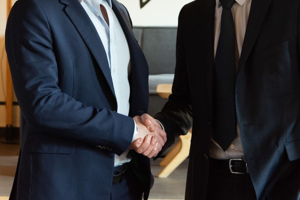 Trouver un avocat en droit des successions Two business partners shaking hands in agreement.